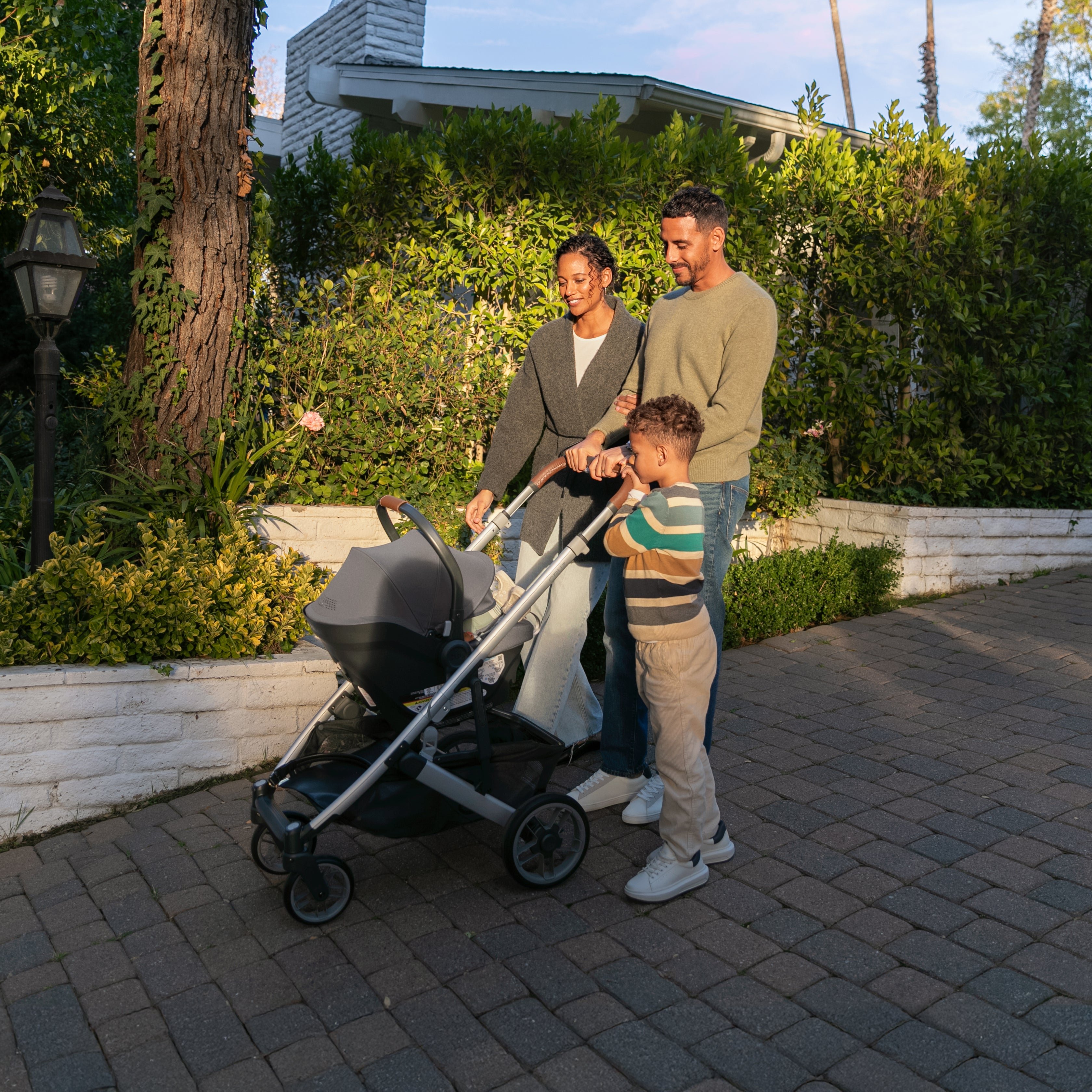 a couple and their child walking a baby in an uppababy stroller