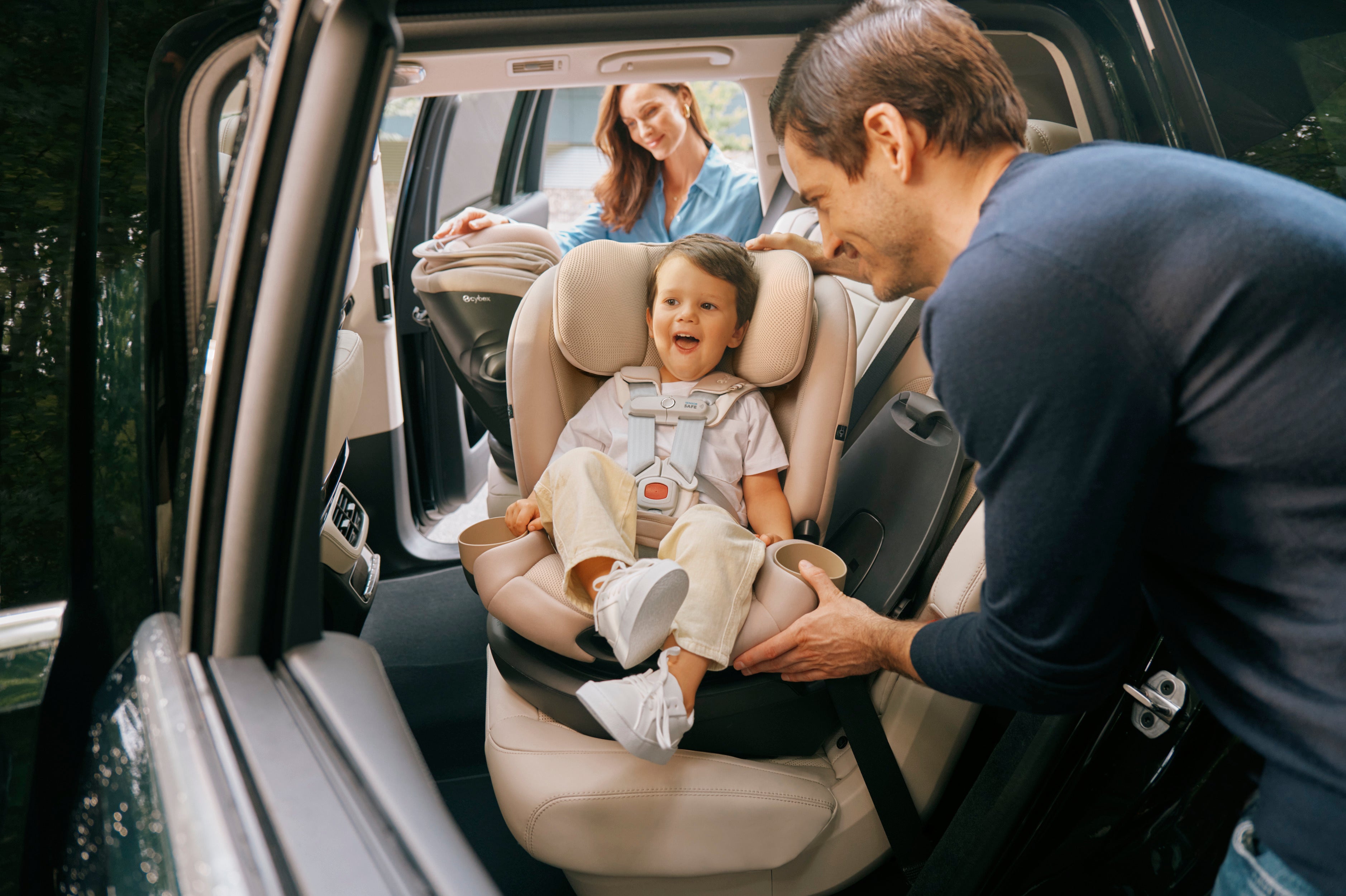 A couple carefully secure a child in the Cybex Callisto G 360 car seat, ensuring safety for their little one during the ride.