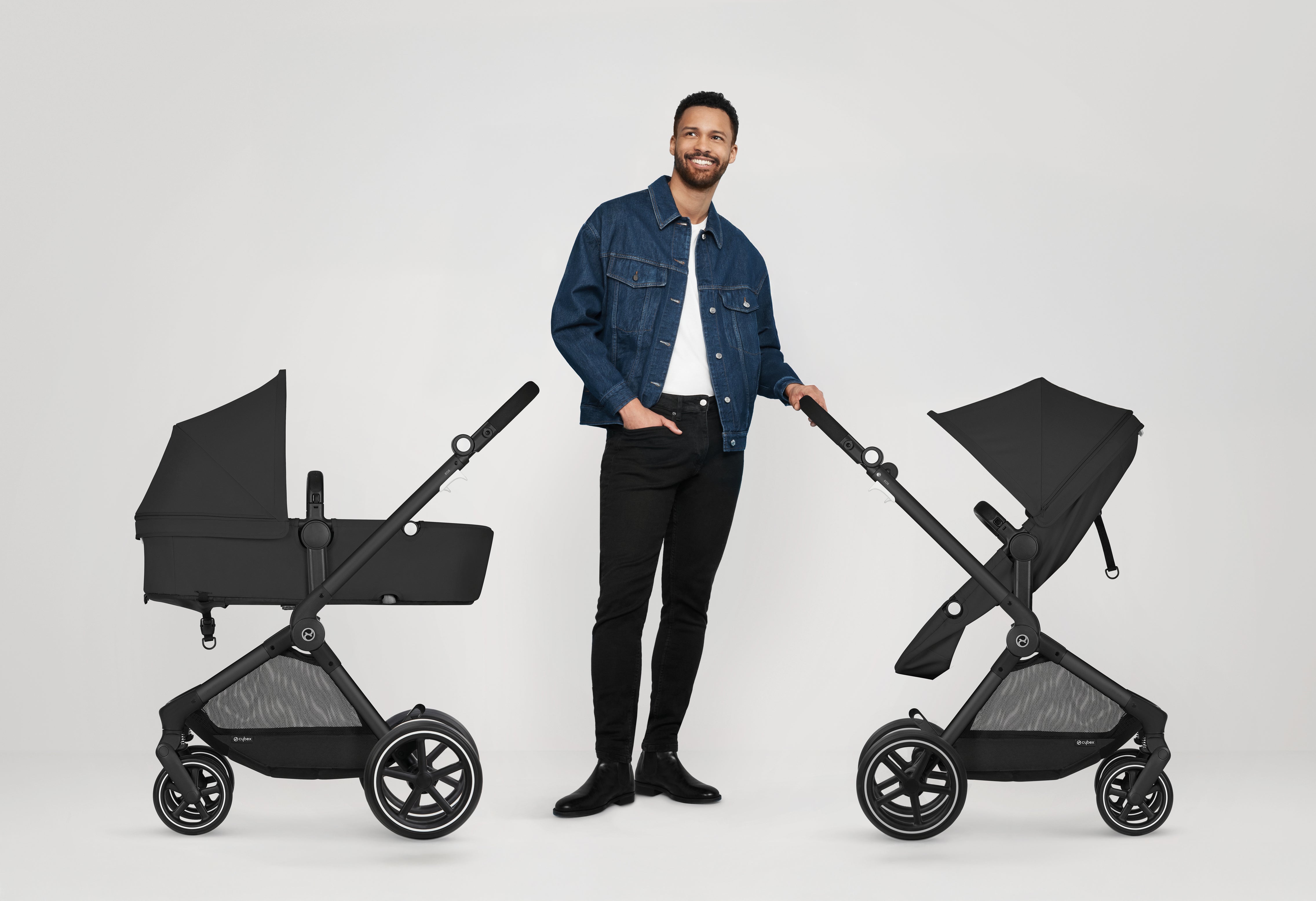 2. A man next to two Cybex EOS strollers, prepared for a fun outing with kids.