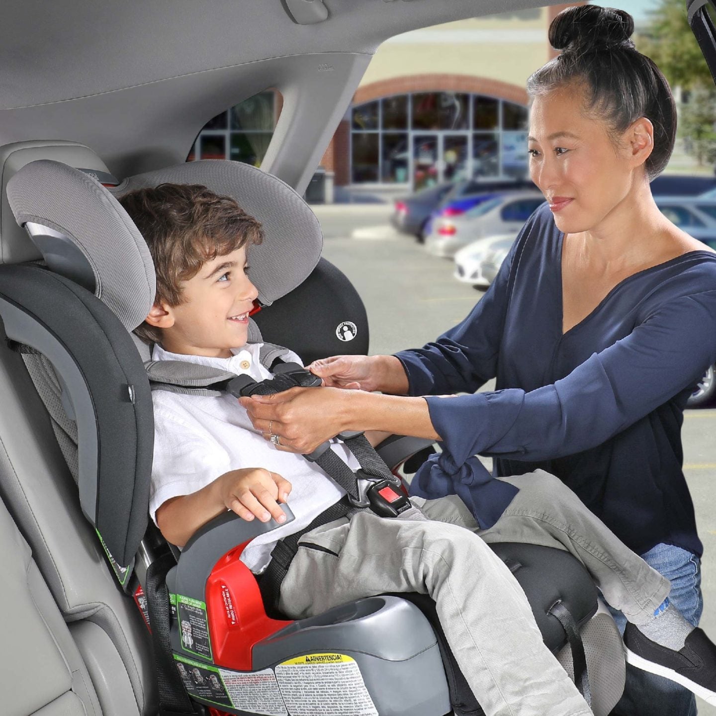 A mother assists a child in the Britax Grow With You car seat, ensuring safety and comfort during their journey.