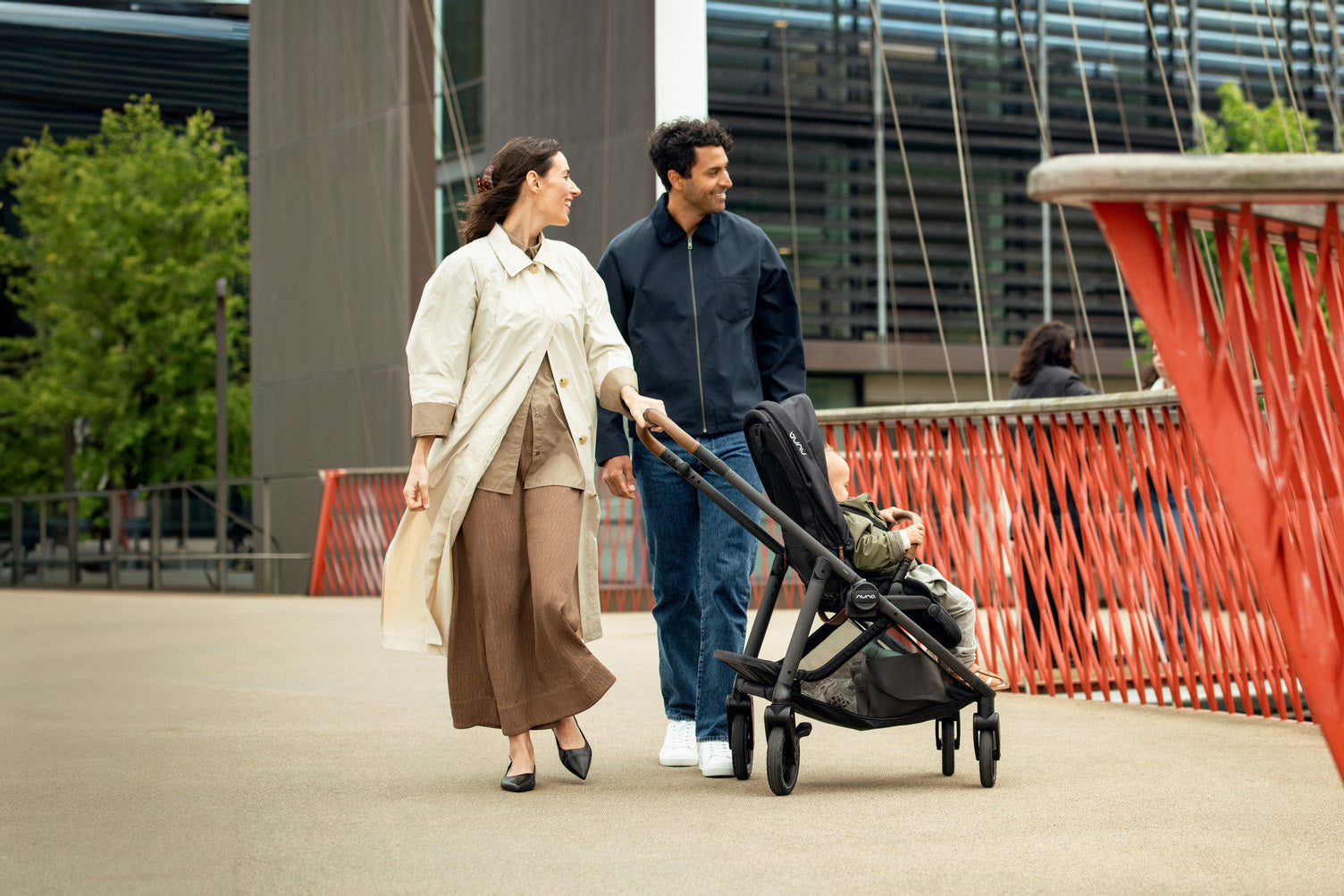 a couple walking their baby in a nuna stroller