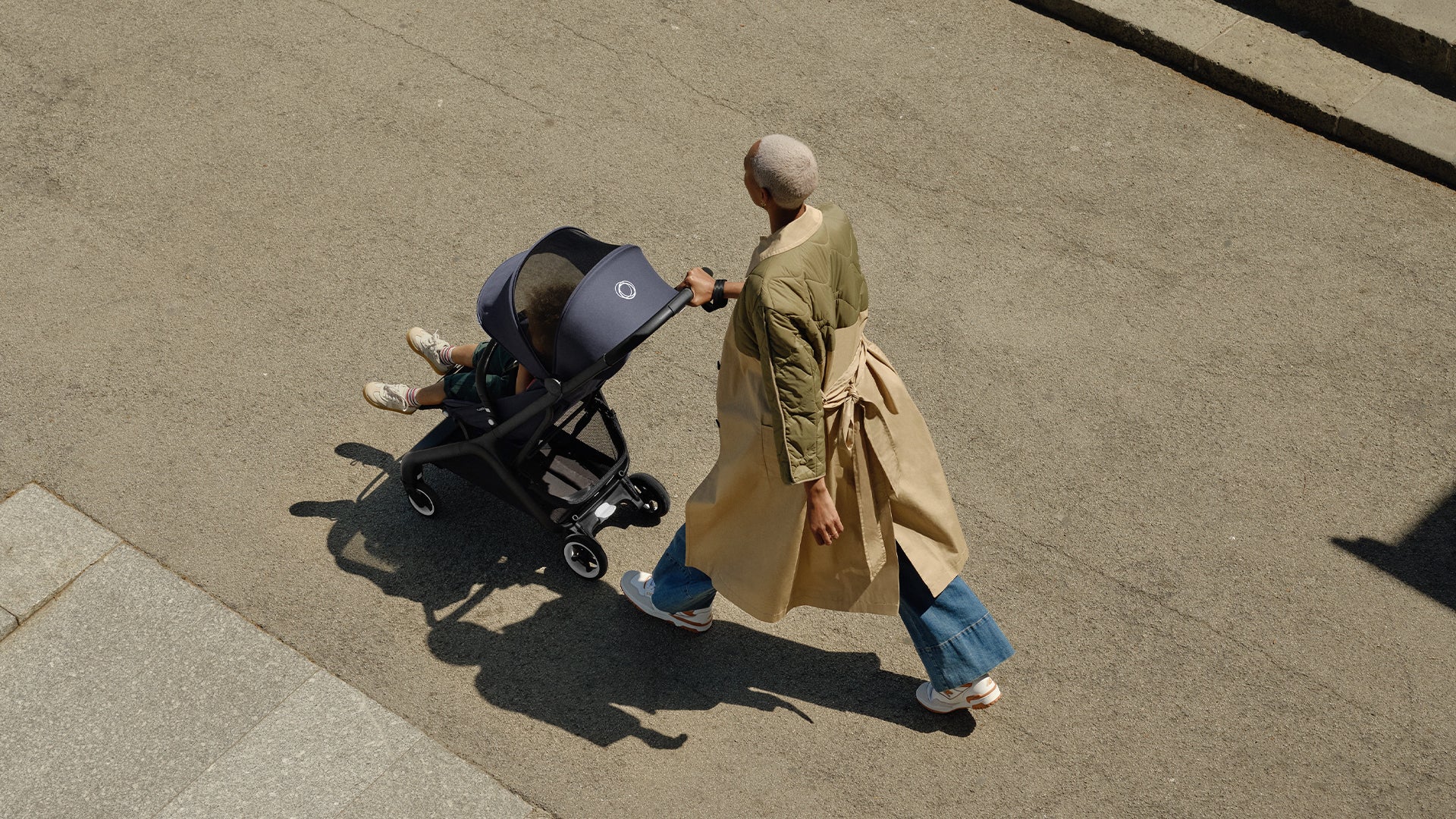 A woman strolling along with her child in the Bugaboo Butterfly stroller, looking content in the fresh air.